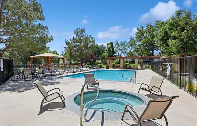 A pool surrounded by chairs and trees.