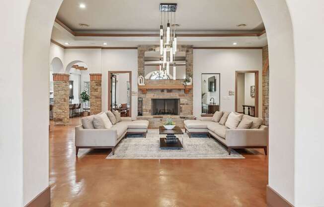 A large, modern resident lounge with a fireplace and a chandelier at Creekside on Parmer Lane Apartments in Austin, TX