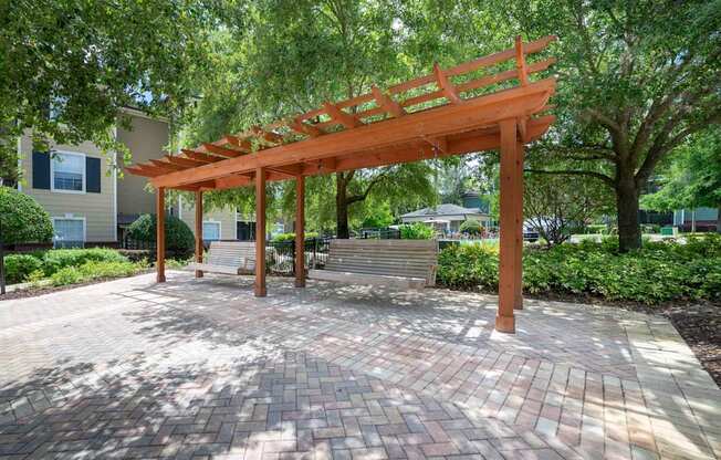 a wooden structure on a brick patio with trees