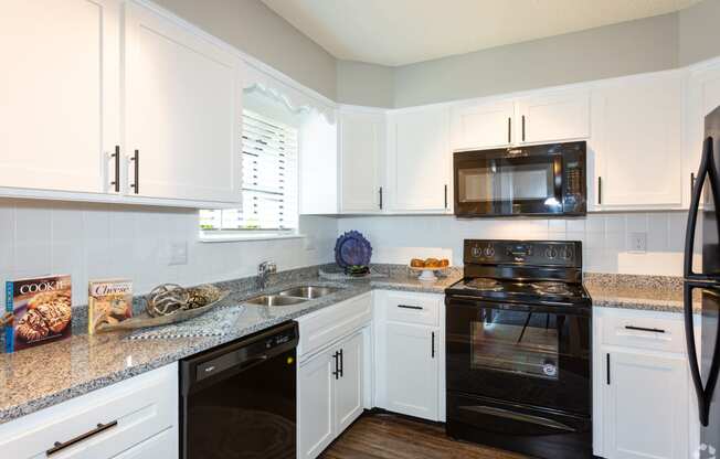 a kitchen with white cabinets and black appliances