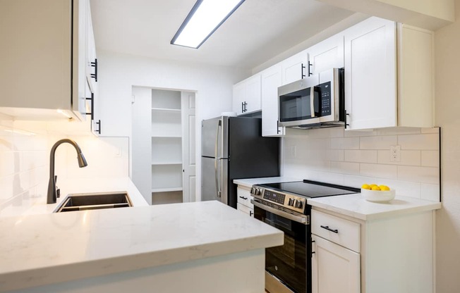A kitchen with white cabinets and black appliances.