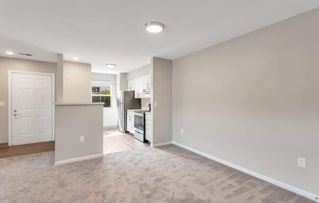 an empty living room and kitchen with a white door