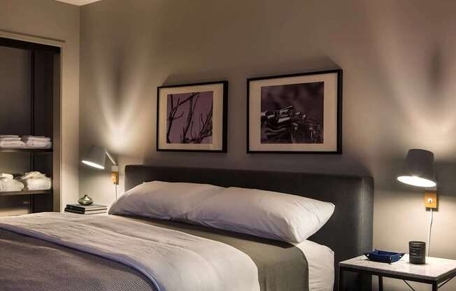 A well-lit bedroom with a large bed and two framed pictures on the wall.