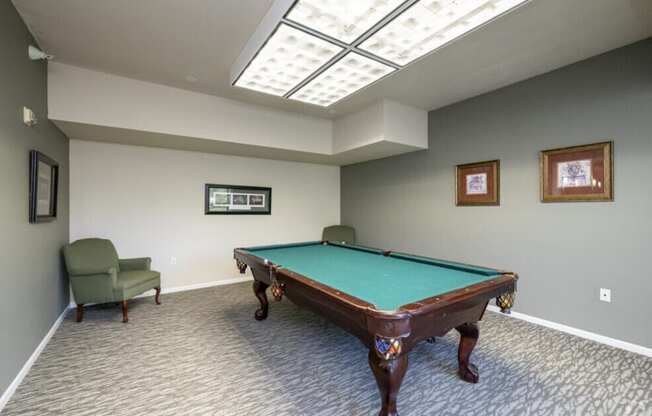 A room with a pool table and a chair.