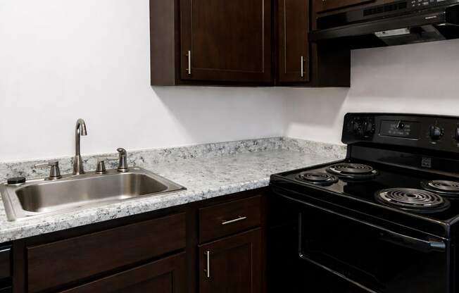 A kitchen with a black stove and brown cabinets.