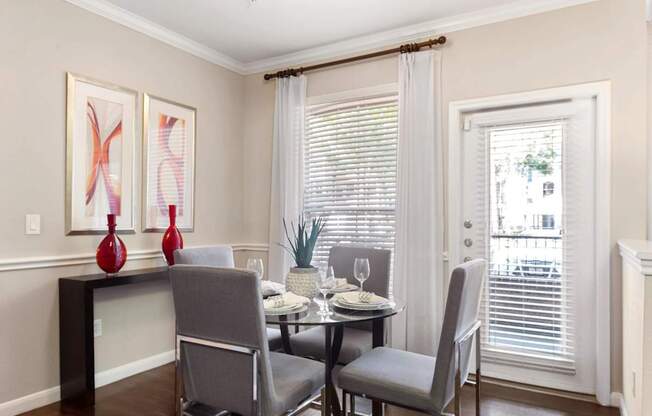 A dining room with a table set for two and two chairs.