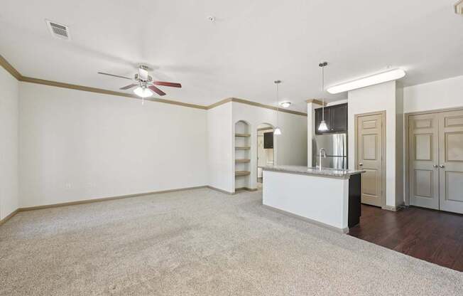 A spacious room with a ceiling fan and a bar area.