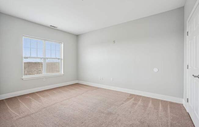 A room with a carpeted floor and a window with blinds.