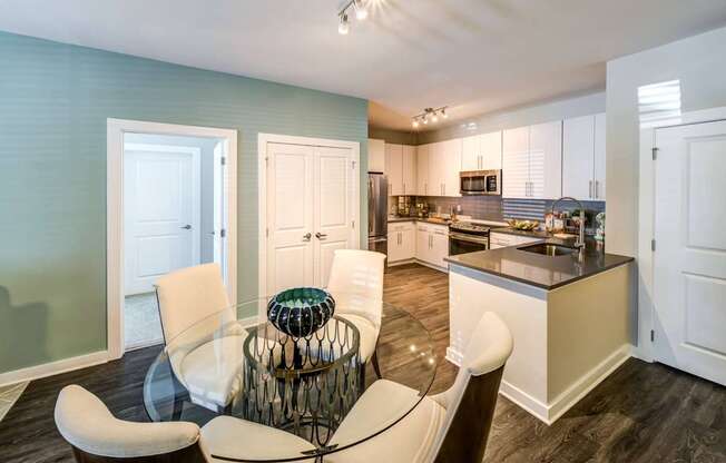 A modern kitchen with a glass table and chairs.