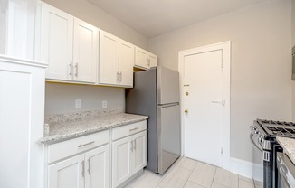 Lewis Manor updated kitchen with white cabinets and a granite countertop.