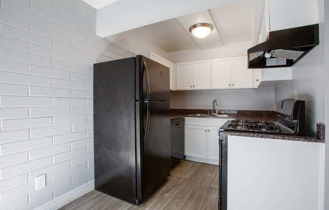 a kitchen with white cabinets and a black refrigerator