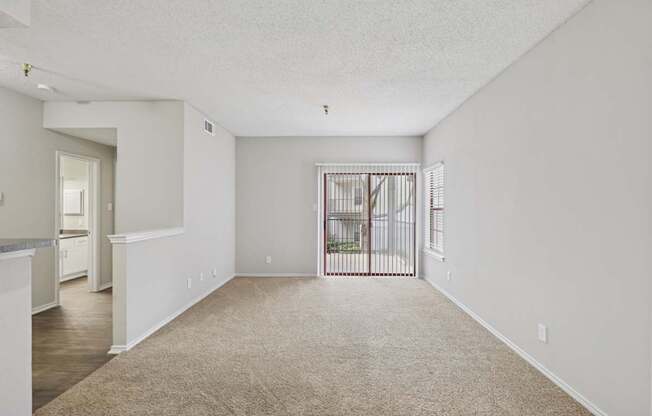B1 living room with plush carpet and sliding door leading to private balcony at Jefferson Place apartments in Irving, TX