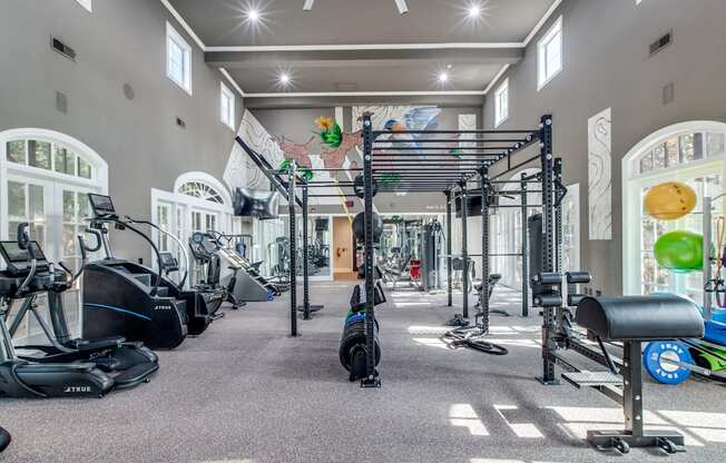 A spacious gym with a variety of equipment including treadmills, stationary bikes, and weight machines.