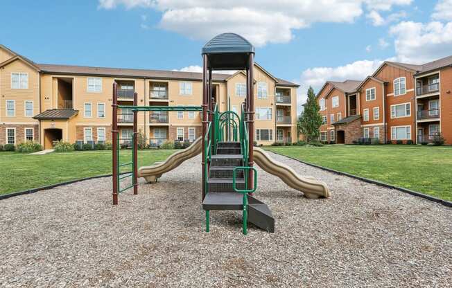 a playground with slides in front of an apartment complex