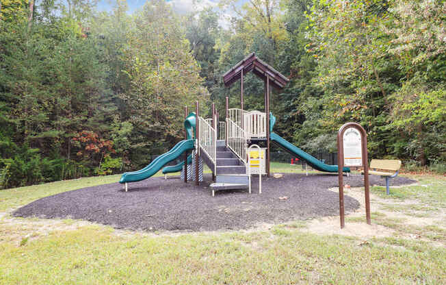a playground with slides in a park with trees