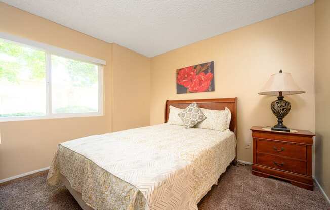 a bedroom with a bed and a nightstand at Oak Terrace Senior Apts, Hemet, 92543