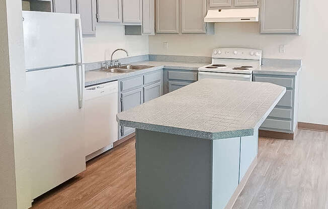 A kitchen with a white refrigerator and a countertop island.