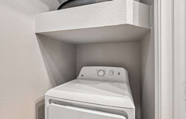 A white washing machine is installed in a wall.
