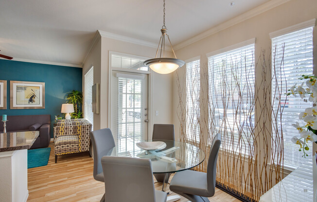 View of Dining Area with Hanging Lamp, Plank-Wood Flooring, and Dining Table at Raveneaux Apartments