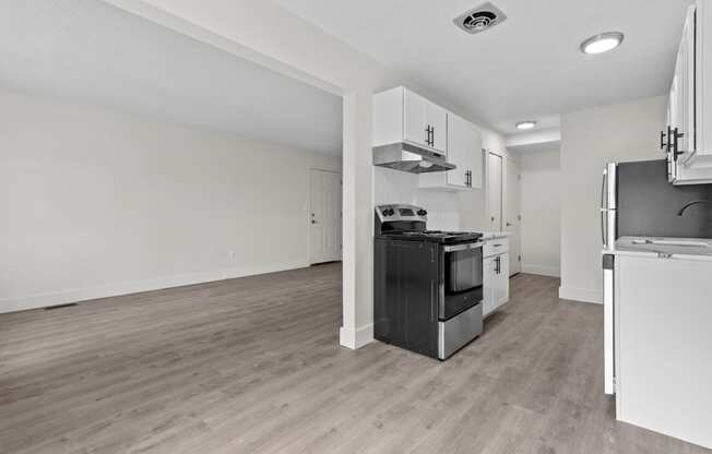 an empty kitchen and living room with white walls and wood flooring