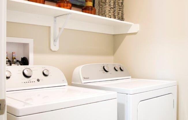 a white washer and dryer in a laundry room with a painting at GrandView Flats and Townhomes, Granger, Indiana, 46530
