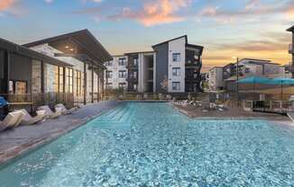 A swimming pool in front of apartment buildings at sunset. at Bridge at Tech Crossing, Austin, Texas