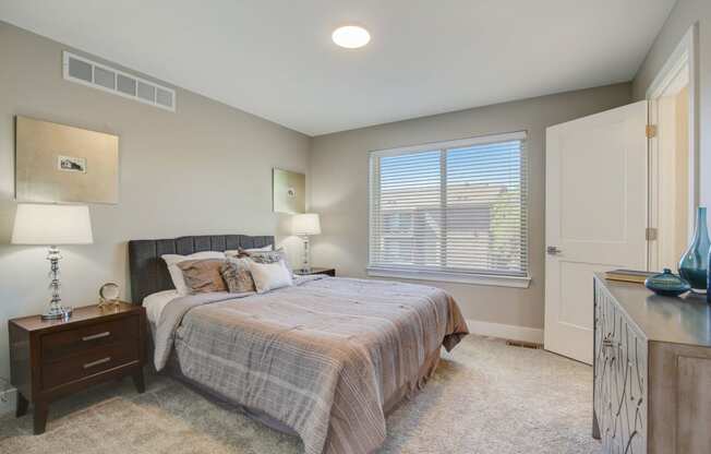 a bedroom with a bed and a window Maple Place Apartments - Southfield MI