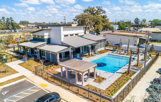 an aerial view of a building with a pool in the foreground and a parking lot in the