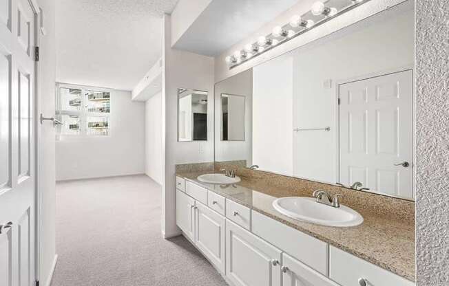 A bathroom with a vanity and a mirror with lights above it. at Towers at Costa Verde Apartments, California, 92122
