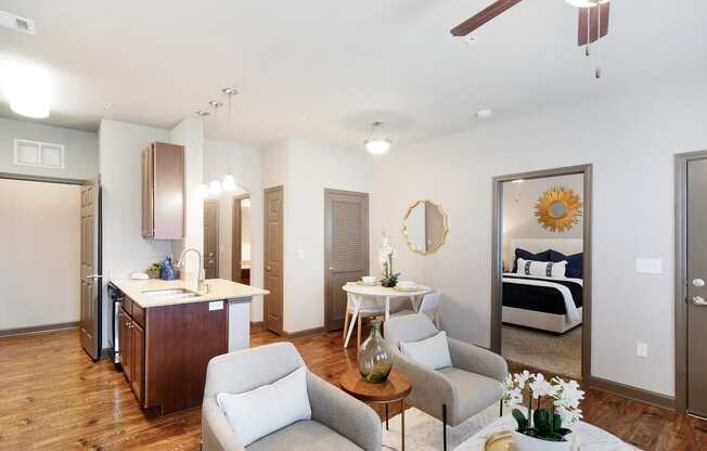 a living room and kitchen with a bedroom in the background