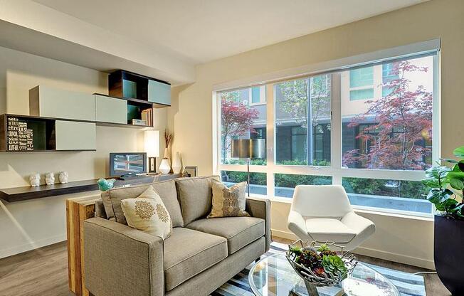 A living room with a couch, chair, and a table with a plant on it. at Kirkland Crossing Apartments, Washington