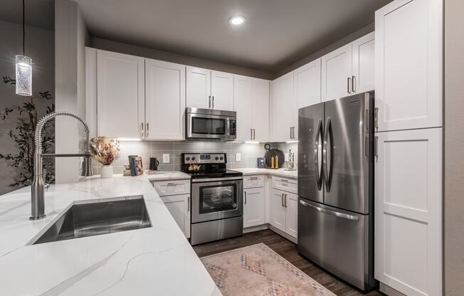 a white kitchen with stainless steel appliances and white cabinets