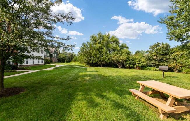 a picnic table in a park with a house in the background