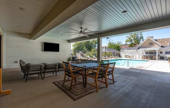 a large patio with a table and chairs next to a pool