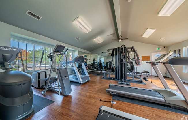 a gym with cardio machines and weights on a wood floor