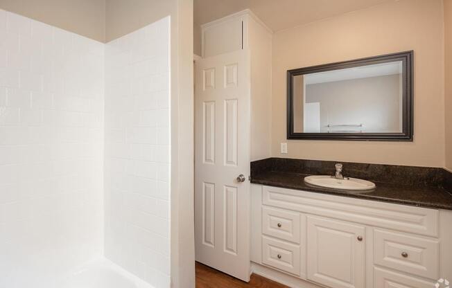 A bathroom with a white door and a black countertop.