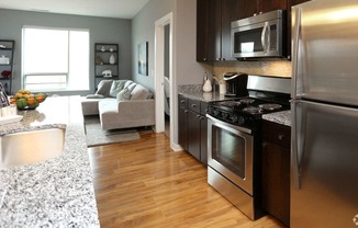 a kitchen and living room with stainless steel appliances and granite counter tops