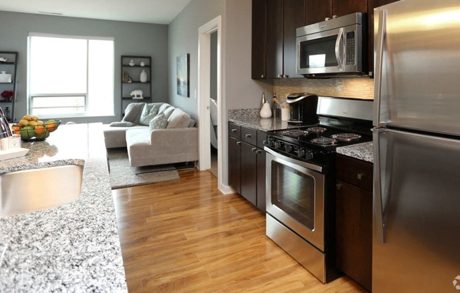 a kitchen and living room with stainless steel appliances and granite counter tops