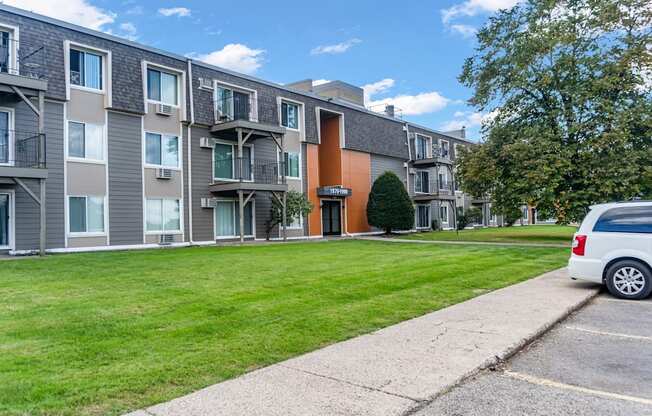 A row of apartment buildings with a white van parked in the driveway.