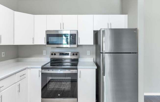 A modern kitchen with a stainless steel refrigerator, oven, and microwave.
