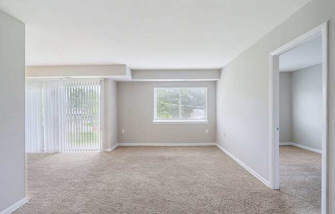 an empty living room with white walls and a window