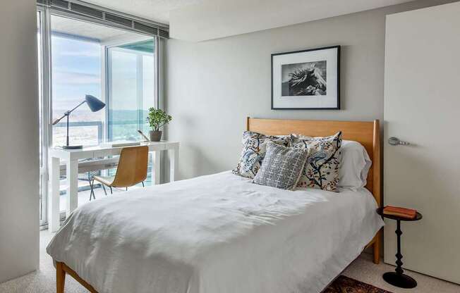 A bedroom with a large bed and a chair by the window.