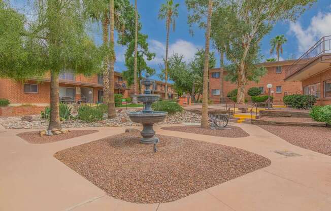 A courtyard with a fountain surrounded by trees and buildings.