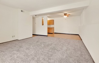 A room with a grey carpet and a ceiling fan.