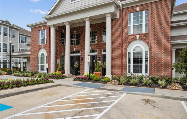 a parking lot in front of a brick building with white columns at Volare at the Woodlands, The Woodlands, 77384