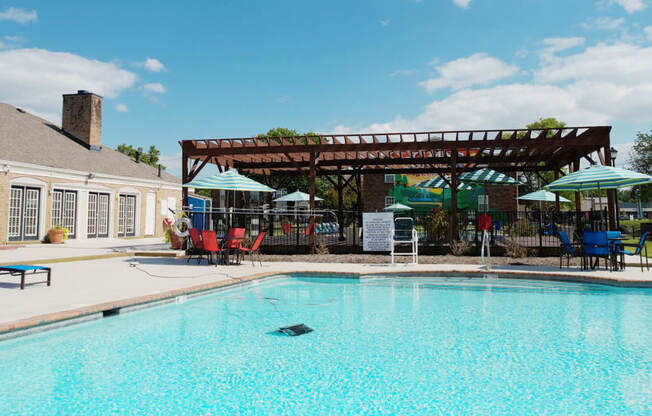 a swimming pool with a patio with chairs and umbrellas