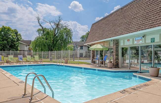 A swimming pool with a diving board and a building in the background.
