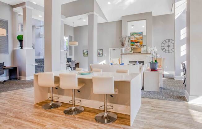 A modern kitchen with white chairs and a bar counter.
