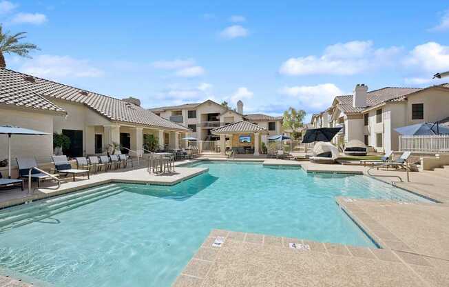 A large swimming pool surrounded by lounge chairs and umbrellas.