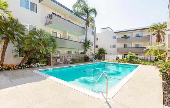 A swimming pool in front of a white apartment building.